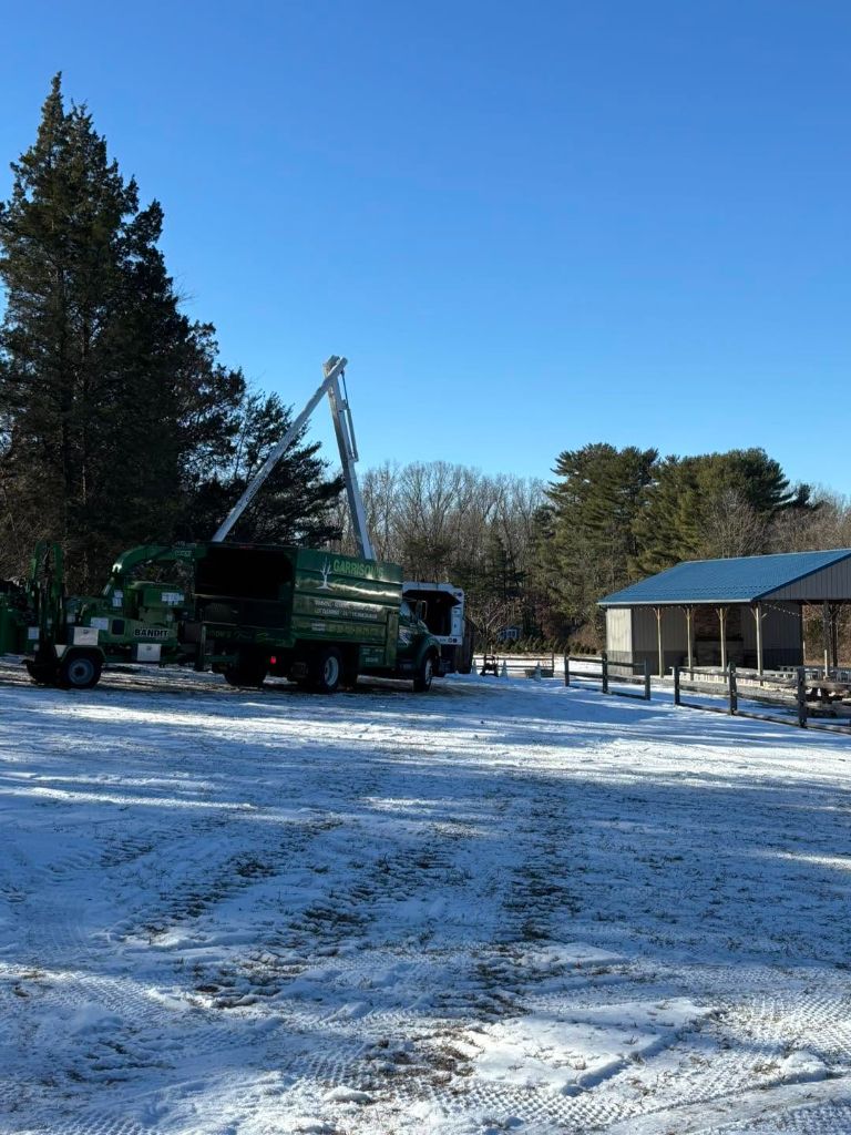 Garrison's Tree Service chipper truck staged near an equipment barn
